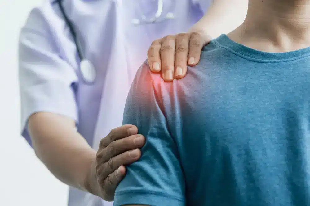 A man with shoulder pain visits a doctor, who examines his arm and shoulder. Concept of physical therapy, rehabilitation, and professional diagnosis.